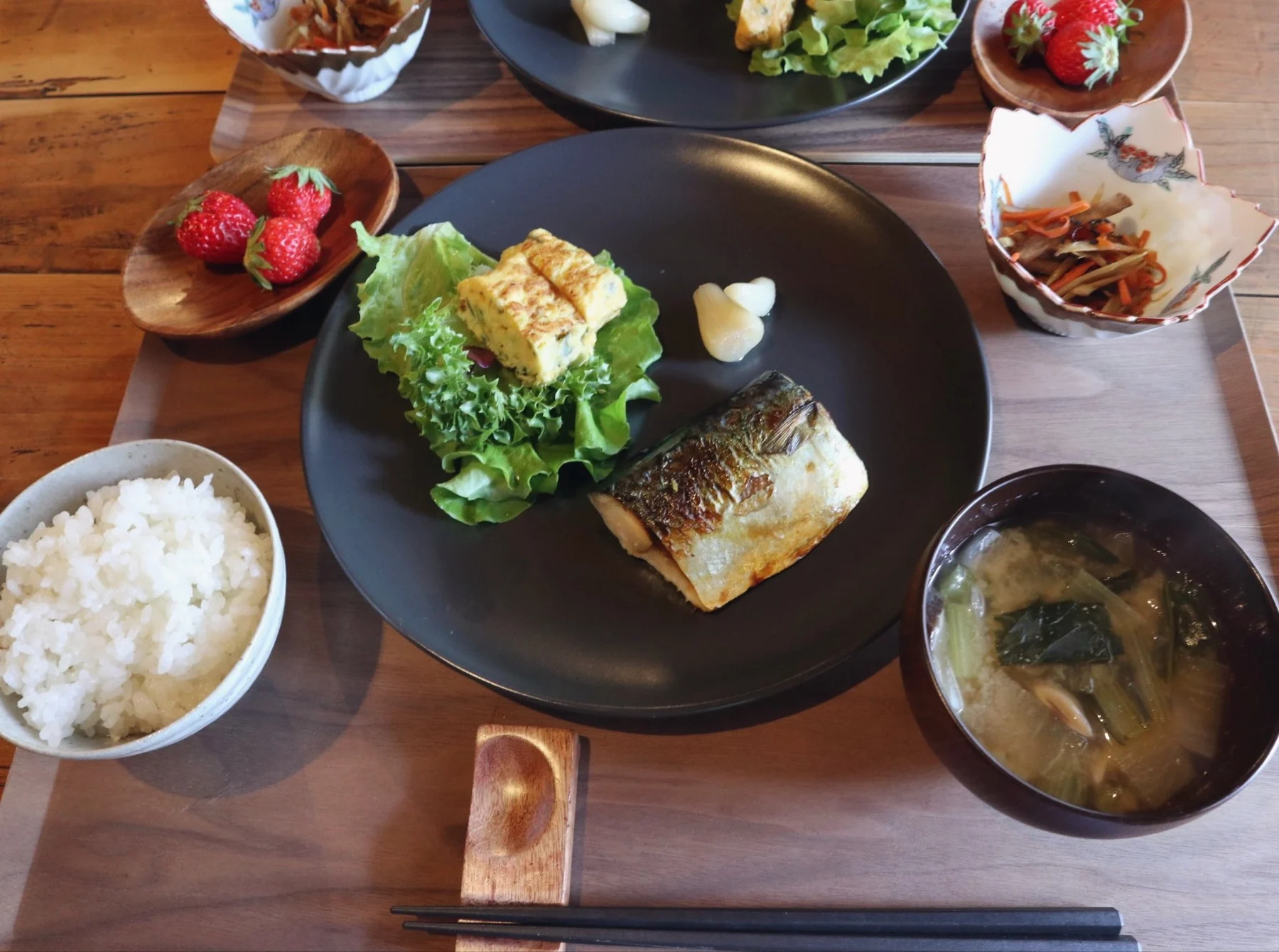焼き魚、卵料理、ごはん、味噌汁などが並ぶ朝食