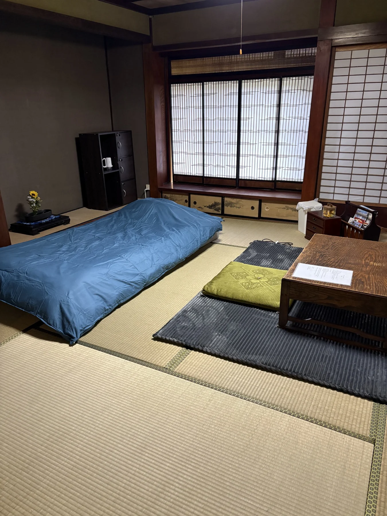 青い寝具と座卓を備えた畳の客室